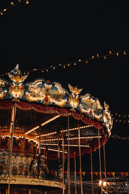 Carrossel mágico infantil dourado brilhante com carrossel de cavalos nas luzes da noite. Vertical