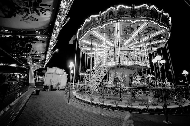 Carrusel infantil en un parque de diversiones por la noche y la iluminación nocturnafoto en blanco y negro