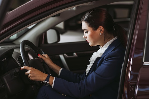 CarSatisfecho felizCliente europea mujer sentada al volante de un auto nuevo