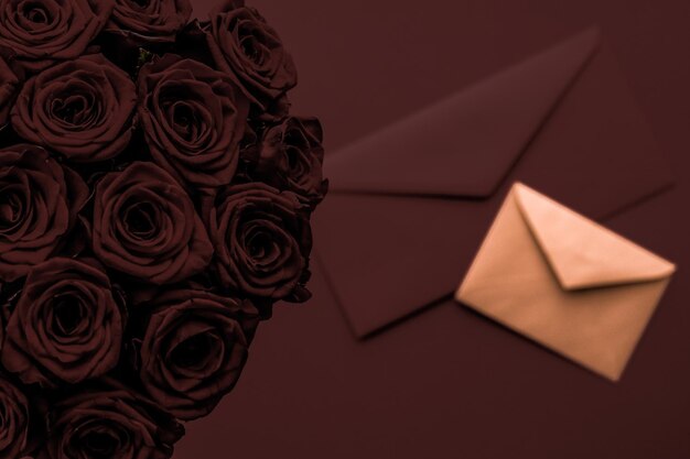 Foto carta de amor y entrega de flores en el día de san valentín ramo de rosas de lujo y tarjeta sobre fondo de chocolate para el diseño de vacaciones románticas