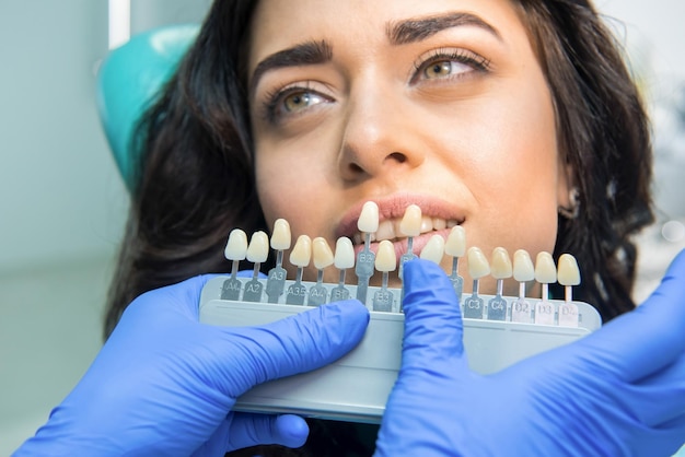 Foto carta de colores de dientes manos de estomatólogo en guantes