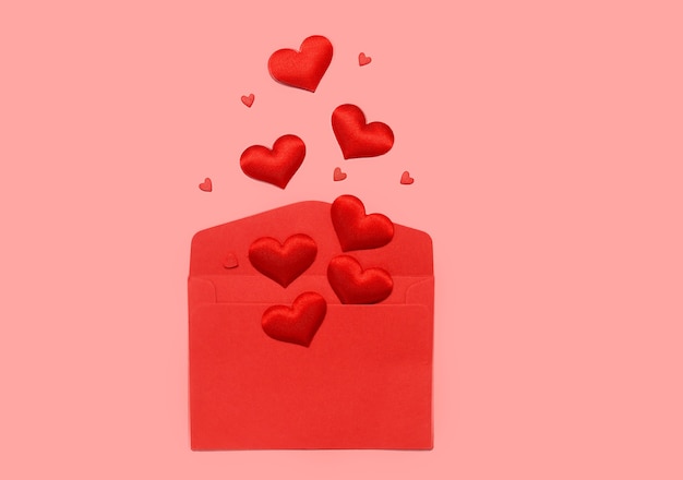 Carta de amor de dia dos namorados. Envelope vermelho em branco e corações em um fundo rosa.