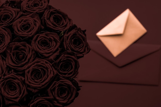 Carta de amor e entrega de flores no buquê de luxo do Dia dos Namorados de rosas e cartão em fundo de chocolate para design de férias românticas