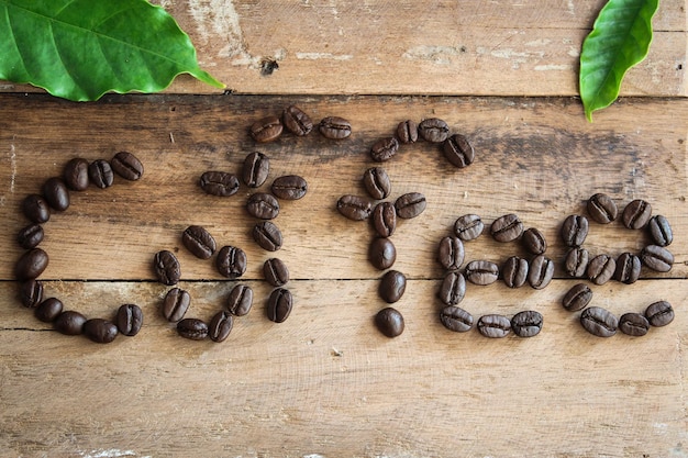 Foto carta de cafeína arranjada com grãos de café sobre fundo de madeira com algum espaço para o seu texto