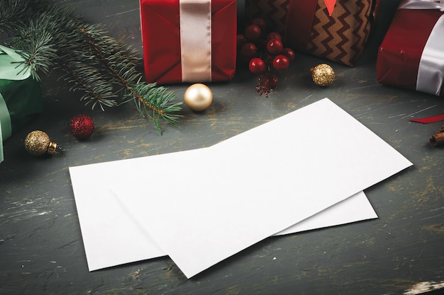 Carta de saudação, envelope e penas rodeado de decorações de natal