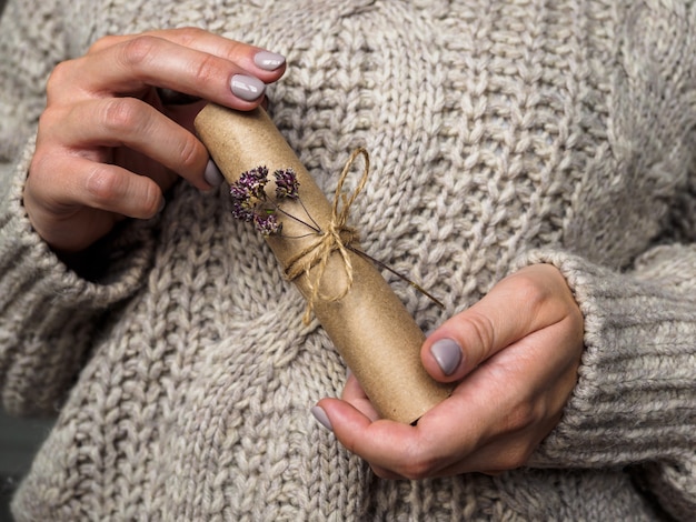 Una carta decorada con una flor de orégano en manos de una niña