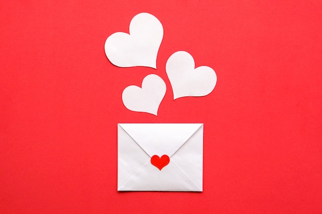 Carta dos namorados e corações brancos sobre um fundo vermelho.