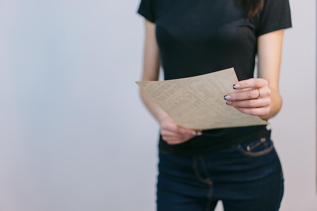 La carta está en manos de una joven de fondo blanco. Una chica con jeans y una camiseta se encuentra en el estudio.