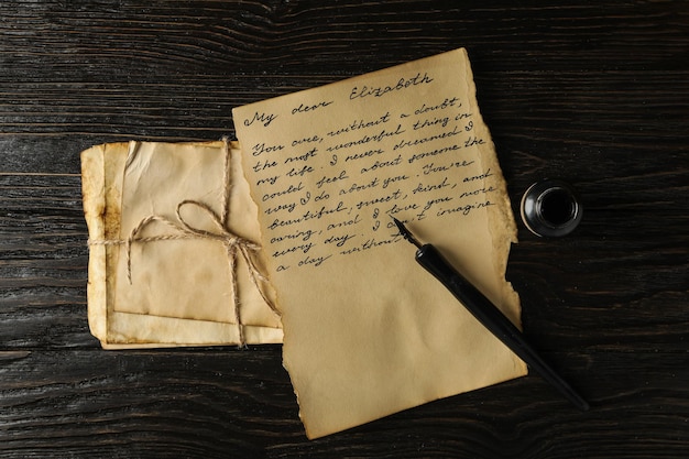 Foto carta de letras antiguas con texto y pluma en la vista superior de fondo de madera
