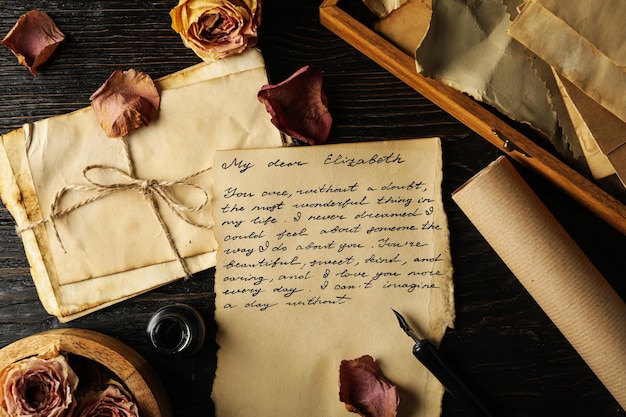 Carta de letras vintage con texto y pétalos de rosa en la vista superior de fondo de madera