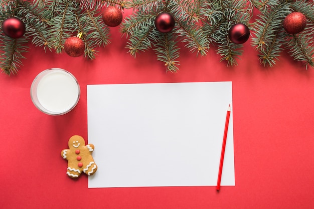 Carta de Navidad para Santa Claus con leche, galletas, pan de jengibre en rojo. Vista superior y espacio para su texto. Endecha plana.