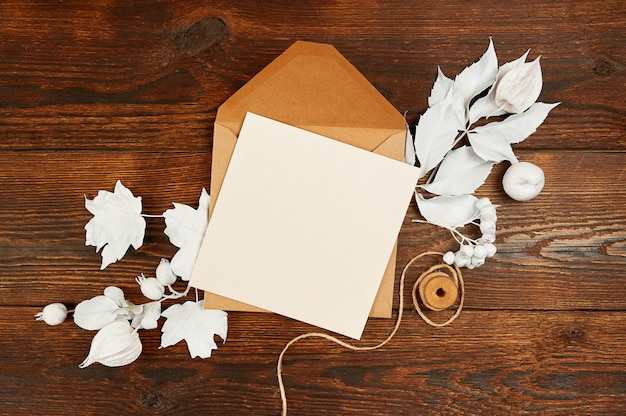 Carta de papel en blanco en sobre verde con copos de nieve de madera y cajas de regalo en mesa de madera