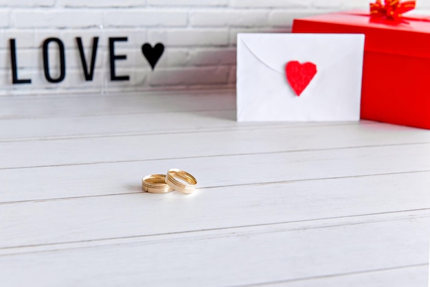 Carta de regalo del concepto del día de san valentín y anillos de boda en la mesa de madera