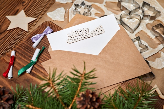 Carta en un sobre con la inscripción feliz navidad sobre fondo de galletas navideñas crudas