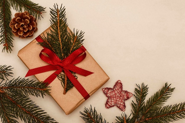 Carta de tarjeta de año nuevo con regalo en una cinta roja y cono de ramas de árbol de Navidad y un juguete de Navidad