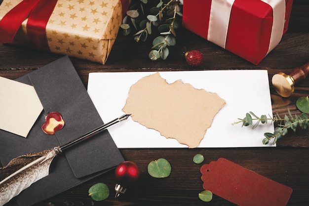 Carta vazia com uma pena na velha de madeira decorada com objetos de Natal