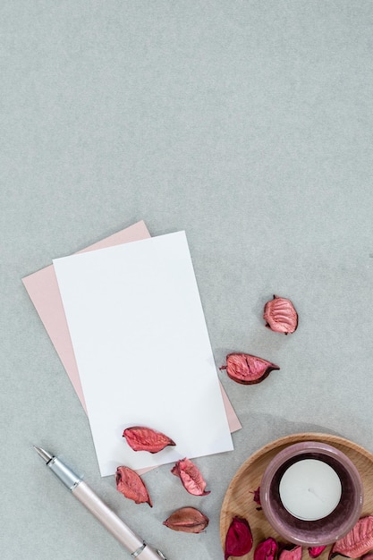 Cartão branco e rosa em branco com velas e pétalas em fundo cinza