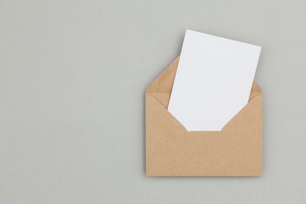 Cartão branco em branco com modelo de envelope de papel kraft pardo simulado