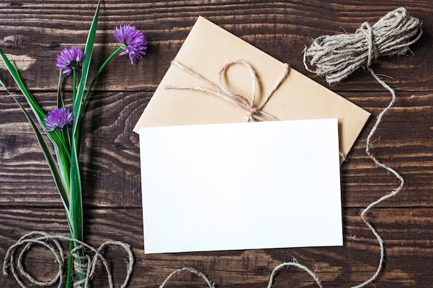 Foto cartão branco em branco e envelope com flores silvestres roxos