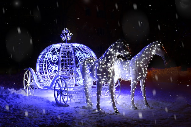 Cartão de ano novo figura luminosa de cavalos com uma carruagem. Neve noite. Lugar para texto