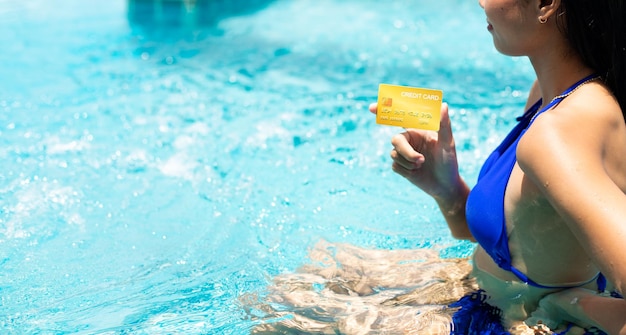 Cartão de crédito em mão de mulher não reconhecida linda garota na piscina sob sol forte