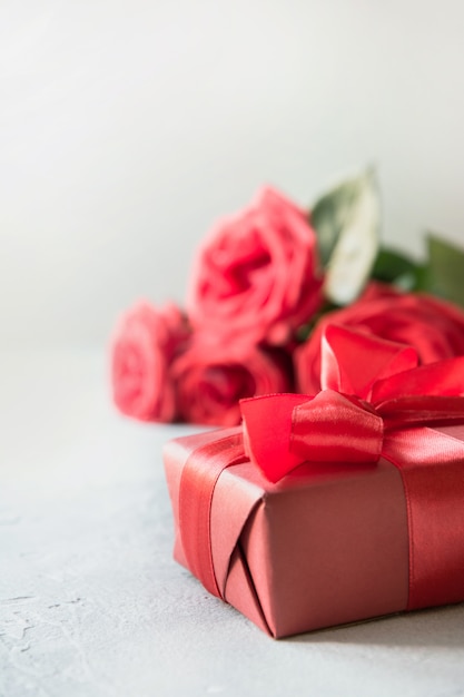 Cartão de dia dos namorados com caixa de presente vermelha, rosas buquê em branco.