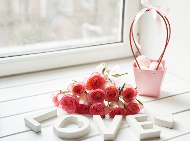 Cartão de dia dos namorados. composição com rosas frescas e molduras para fotos no peitoril da janela. espaço para texto. composição floral com inscrição amor. dia das mães e 8 de março cartão