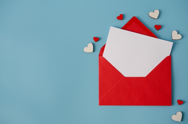 Cartão de dia dos namorados. Envelope vermelho com cartão em branco sobre fundo azul.