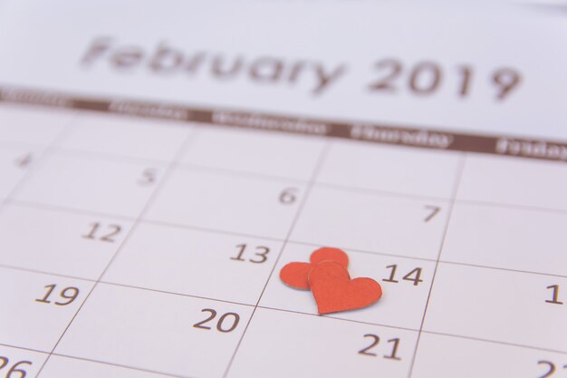 Cartão de dia dos namorados. Papel de corações vermelhos na página de calendário 14 de fevereiro com espaço de cópia
