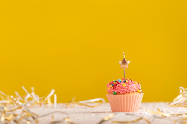 Cartão de férias com cupcake com velas em fundo amarelo brilhante e lugar para o seu texto.