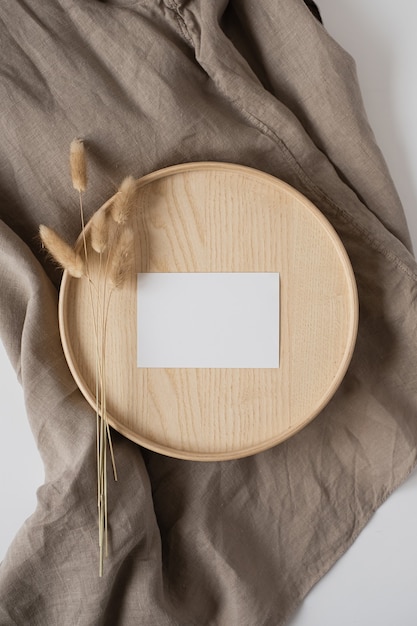 Cartão de folha de papel em branco com cauda de coelho no caixão de madeira e manta de linho cinza.