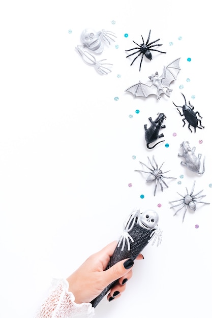 Cartão de Halloween em branco com decoração de férias em preto e prata. Mulher com manicure preta segurando um cone preto com morcegos e fantasmas voando por aí, cópia espaço, férias góticas, imagem vertical