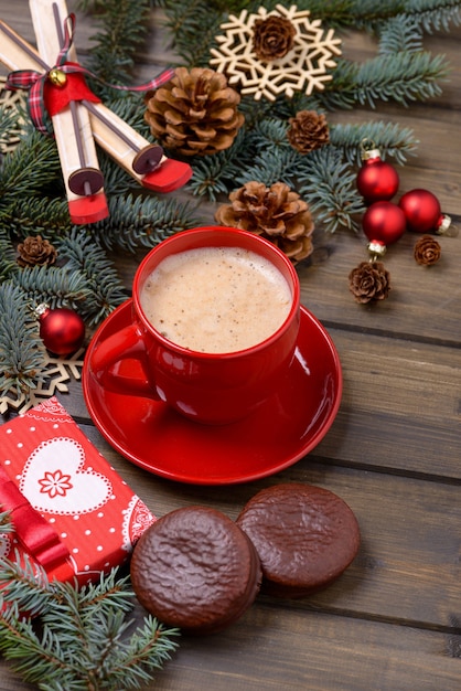 Cartão de natal com árvore de abeto e cones com café e biscoito em fundo de madeira