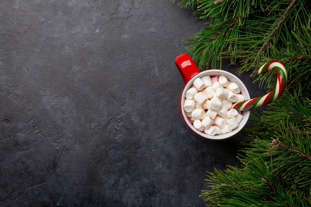 Cartão de Natal com árvore de abeto e xícara de cacau com bastão de doces de marshmallow em fundo de pedra com espaço de cópia para suas saudações de Natal Vista superior plana leiga