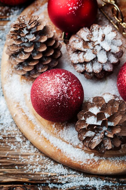 Cartão de Natal com cones e bolas vermelhas na mesa de madeira