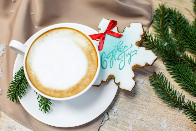 Cartão de natal e feliz ano novo com uma xícara de café, pinho, ramo de abeto e pão na mesa de madeira