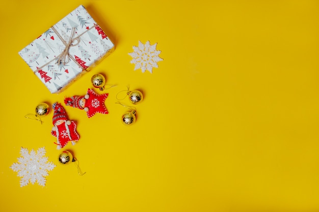 Cartão de Natal laranja com vermelho de brinquedo de malha estrelas de Natal em chapéus engraçados e caixas de presente branca. Postura de Natal plana.