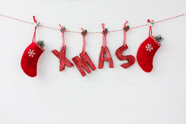 Cartão de Natal. Letras de madeira vermelhas formando a palavra Natal e meias vermelhas de Natal em fundo branco de madeira. Copie o espaço