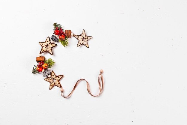 Cartão de Natal. Mesa isolada branca com pinhas, galhos, estrelas de madeira.