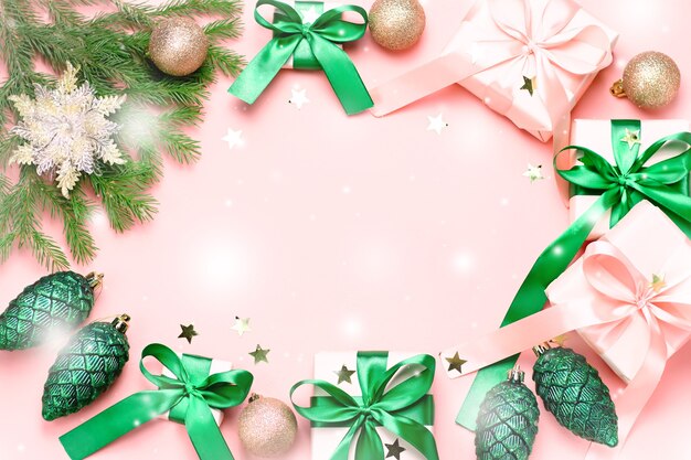 Cartão de Natal rosa ou plano de fundo de ano novo, plana leigos, copie o espaço. Caixas de presente em rosa pastel e enfeites verdes e dourados na mesa rosa, vista superior. Presentes de natal ou conceito de compras de natal