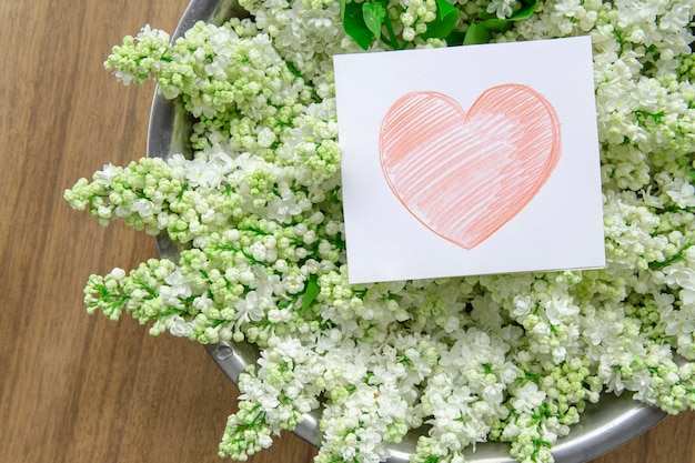 Cartão de papel branco com flores lilás brancas closeup