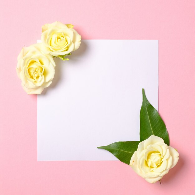 Foto cartão de papel em branco com pétalas de flores rosa sobre fundo rosa pastel.