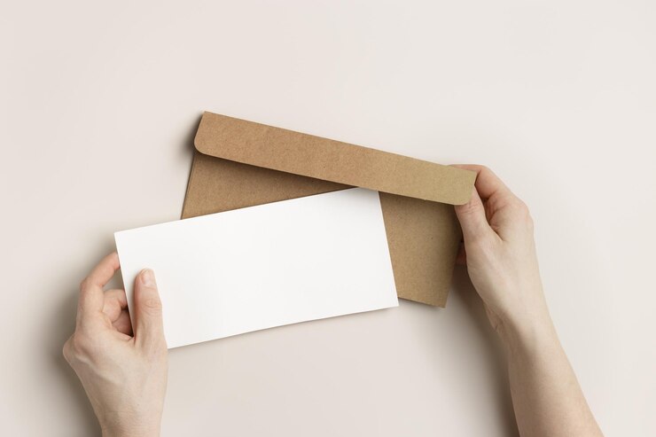 Foto cartão de papel em branco maquete em mãos de mulher envelope de artesanato em fundo bege convite branco vazio na mesa carta de papel aberta feminina foto de estilo de vida minimalista espaço de cópia de vista superior plana