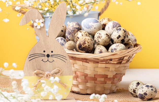Cartão de Páscoa Cesta de coelho de madeira cheia de ovos de codorna flores brancas frescas em amarelo