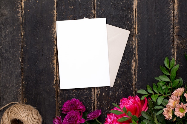 Cartão de presente branco com lindas flores em uma mesa escura vintage