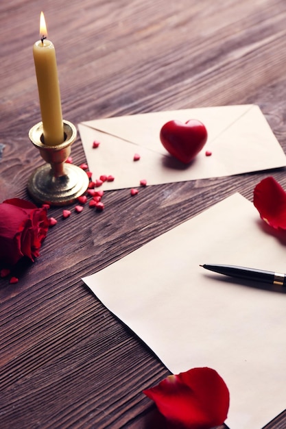 Foto cartão de presente para o dia dos namorados com caneta rosa vermelha e vela em fundo de madeira