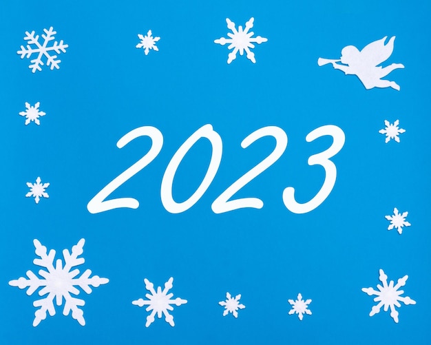 Cartão de saudação de Ano Novo A data do calendário 2023 em um fundo azul com flocos de neve de Natal um anjo branco