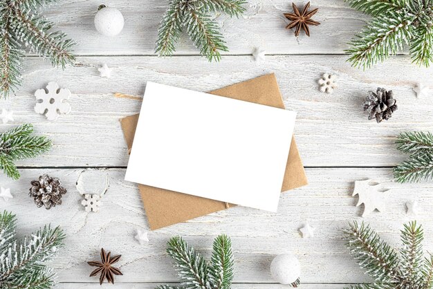 Cartão de saudação de Natal em moldura feita de decorações de férias de abetos em fundo branco de madeira Mock up