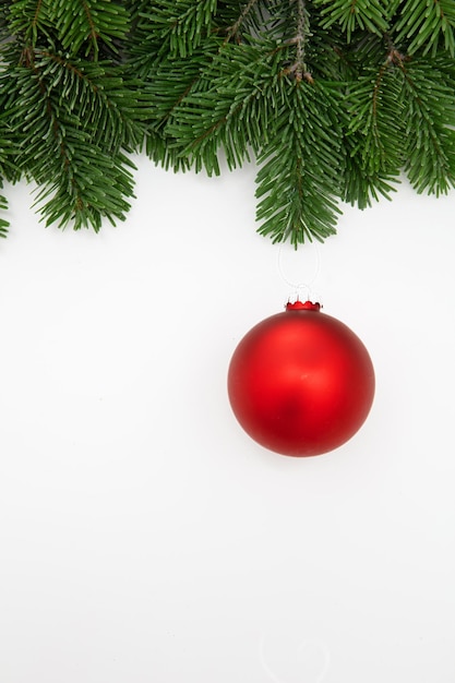 Cartão de saudação de Natal vermelho Xmas bauble em galho de abeto isolado em fundo branco