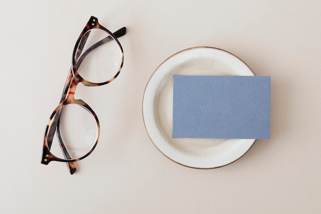 Cartão de visita azul em um prato com maquete de óculos